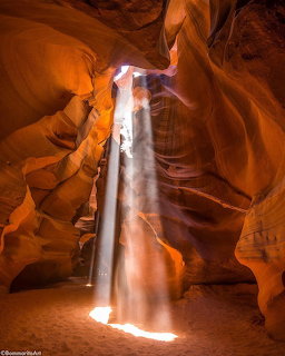 Sunlight beam shining through narrow slot canyon with orange and red sandstone walls