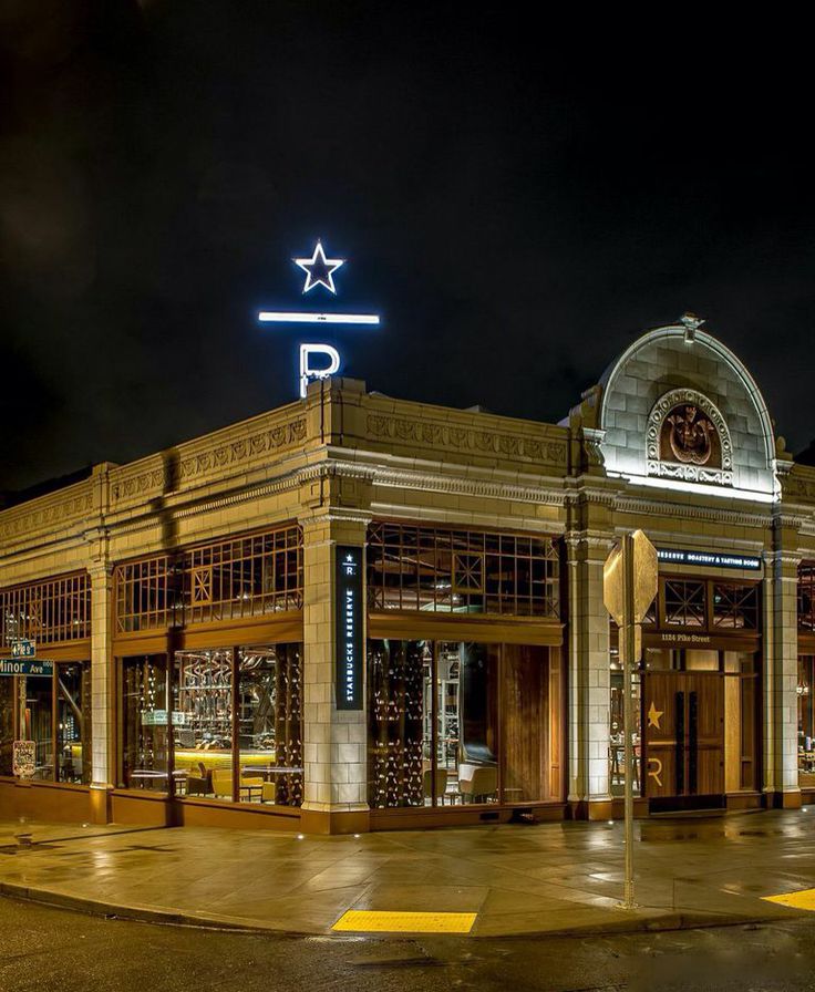 Starbucks Reserve Roastery exterior at night with glowing star and R sign on a corner building