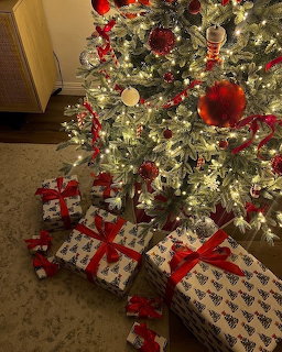 Decorated Christmas tree with red ornaments and wrapped gifts with red bows beneath it