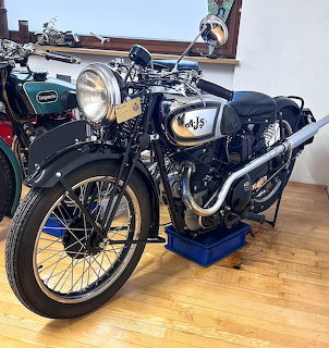 Vintage AJS Silver Streak 350cc motorcycle on blue display stand indoors
