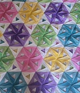 Colorful quilt with kaleidoscope star pattern blocks in multiple colors arranged in grid layout