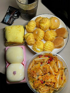 Korean food spread with twisted donuts, white buns, rice cakes, and tteokbokki on plates