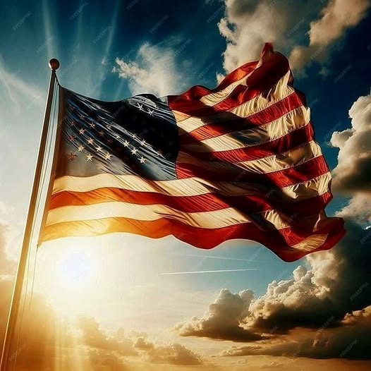 American flag waving dramatically against a sunset sky with clouds