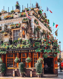 The Churchill Arms pub in London, covered with flowers, hanging baskets, and flags.