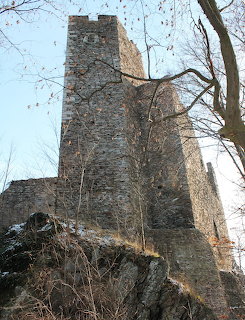 Medieval stone castle tower on rocky hill with bare trees