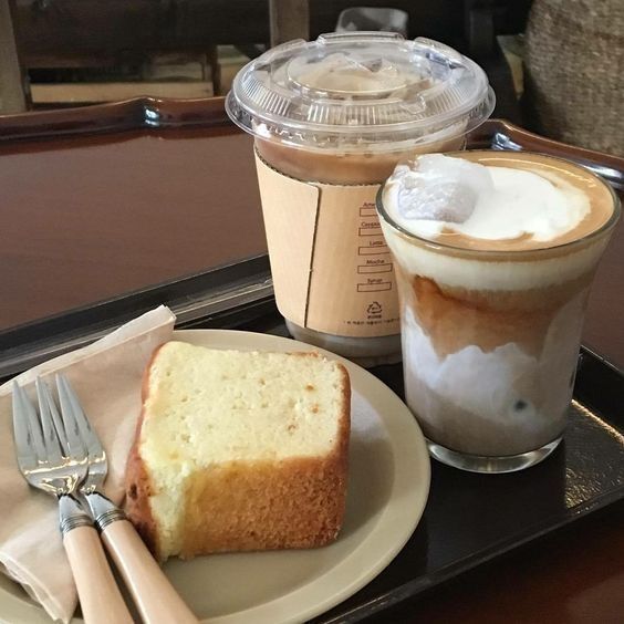 Two coffee drinks with a slice of pound cake on a cafe tray