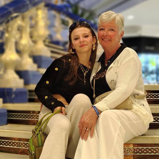 Two women sitting together smiling in a shopping mall with decorative background