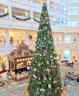 Large Christmas tree in white multi-story hotel lobby with decorative gingerbread house