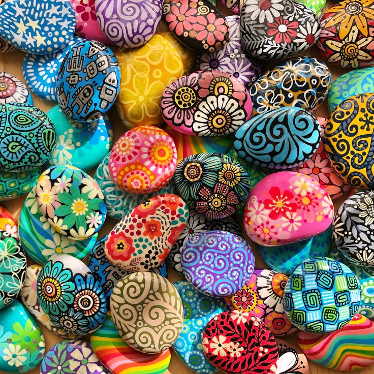 Collection of colorful painted pebbles with mandala and floral patterns in various bright colors