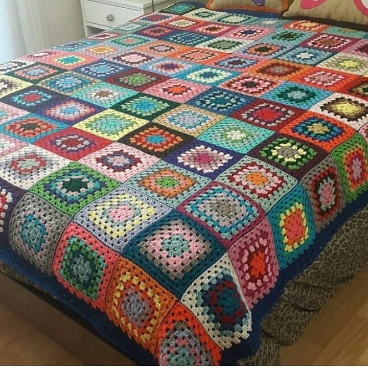 Colorful crocheted patchwork blanket made of granny squares covering a bed
