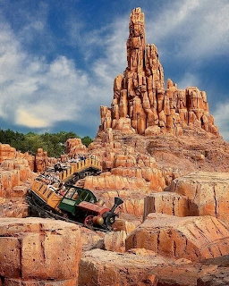 Roller coaster train emerging from rugged red rock formations at Big Thunder Mountain Railroad