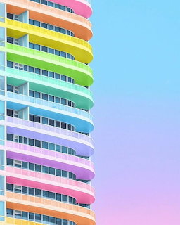 Pastel rainbow high-rise building with curved balconies against a gradient sky
