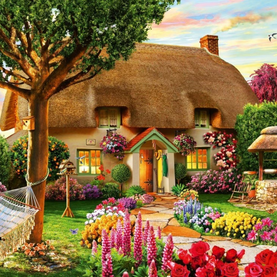Thatched roof cottage with colorful flower garden at sunset